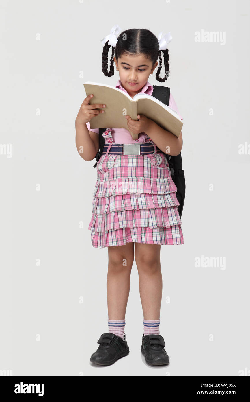 Schoolgirl standing with backpack and reading a book Stock Photo - Alamy