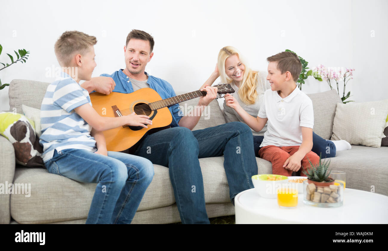 Happy caucasian family smiling, playing guitar and singing songs together at cosy modern home Stock Photo