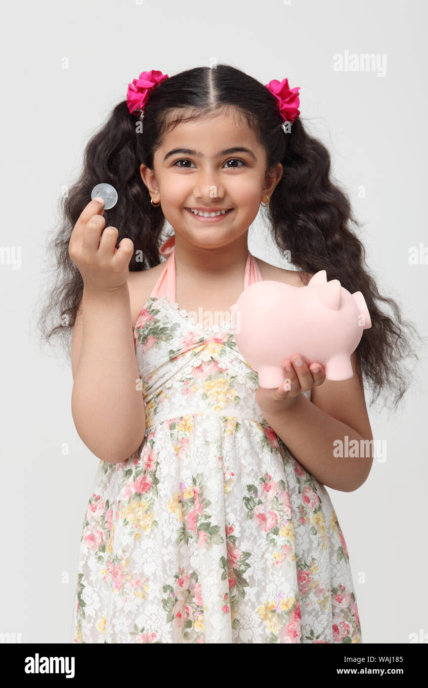 Girl holding a coin with a piggy bank Stock Photo - Alamy