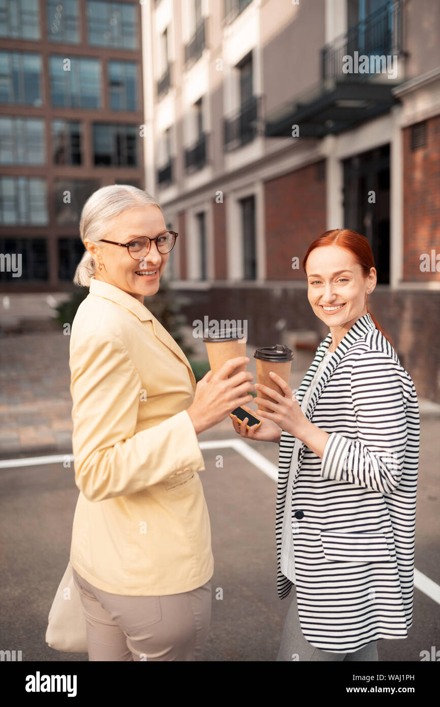 Two smiling businesswomen standing in front of an office building Stock ...