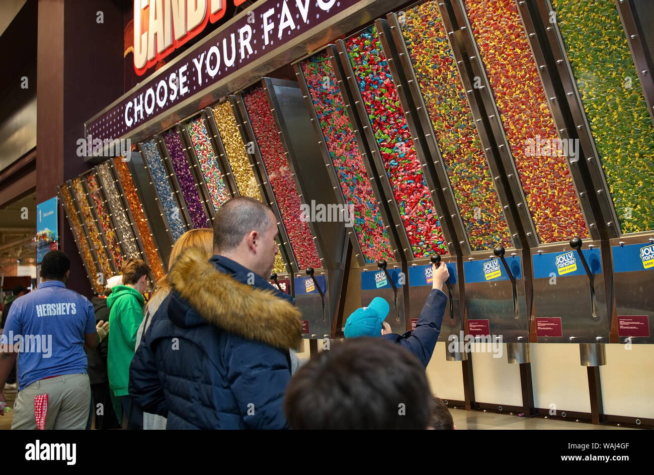 Hershey, PA USA. Mar 2019. Mom and dad watching as excited son dispenses candy into a loot bag. Stock Photo
