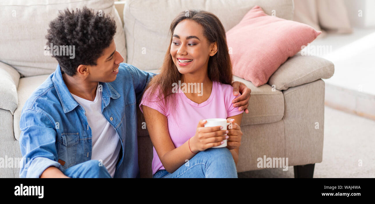 Teenagers talking and drinking coffee, sitting on floor at home Stock Photo