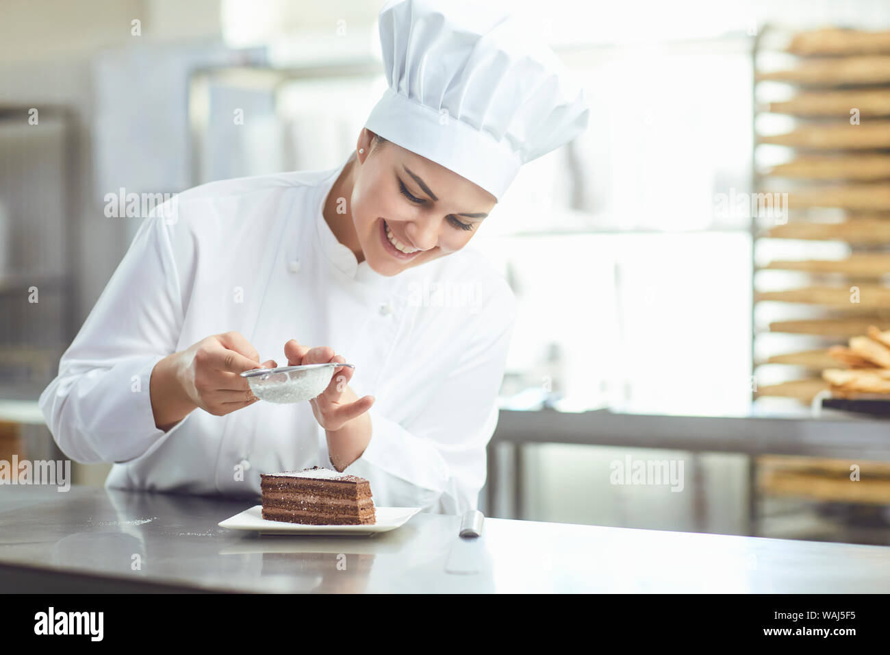 Confectioner decorating chocolate cake in pastry shop. Stock Photo