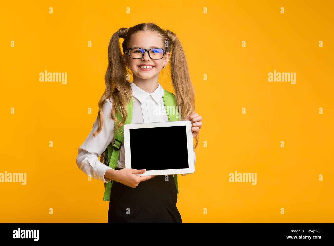 Elementary Student Girl Showing Blank Tablet Screen, Yellow Studio Background Stock Photo Alamy