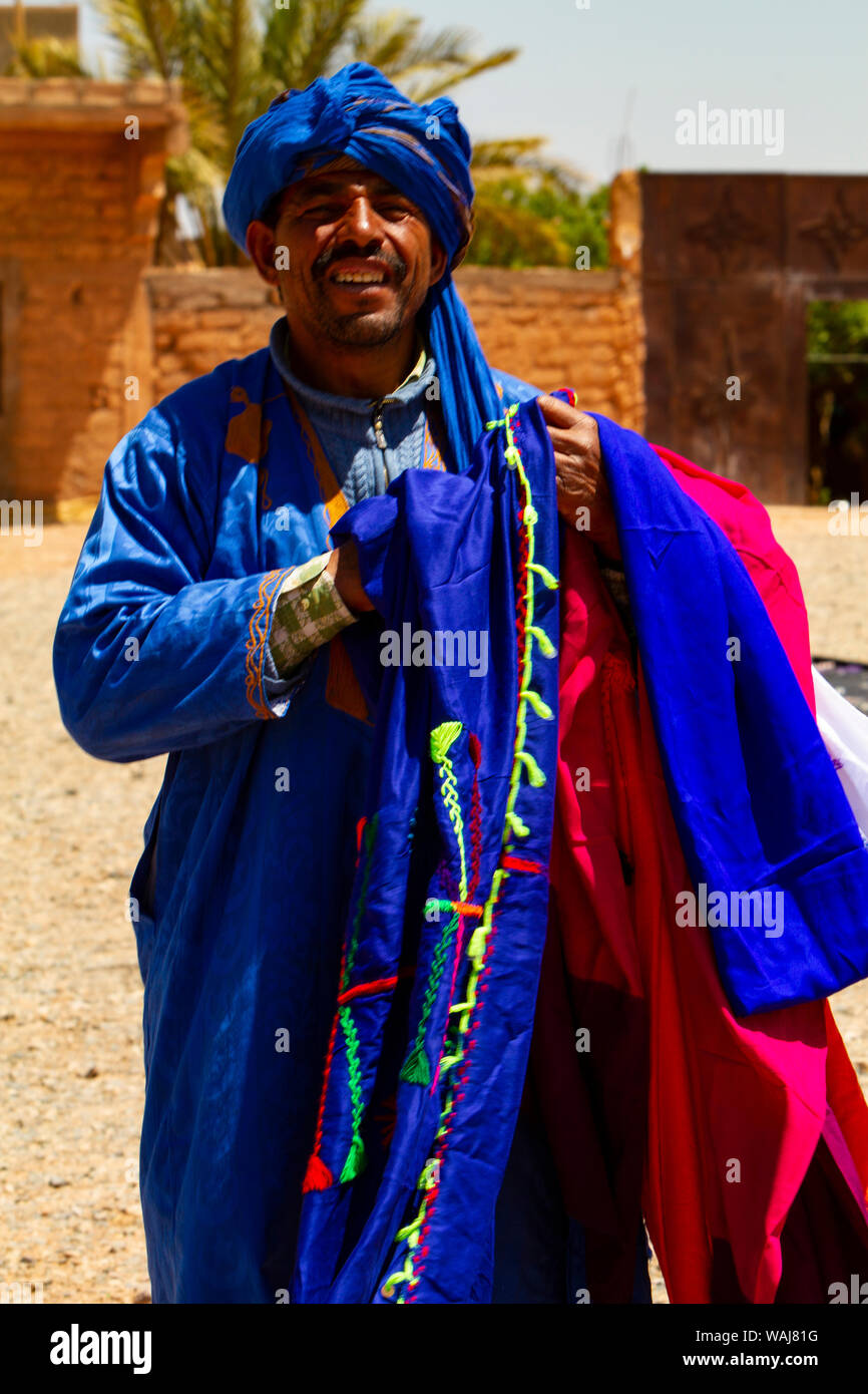 Merzouga, Erg Chebbi, Sahara Desert, Morocco. Moroccan man selling woven textiles Stock Photo