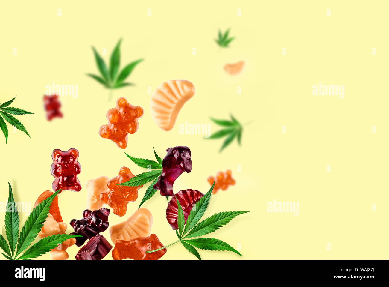 Chewing candies, marmalade with CBD oil and THC. Colored marmalades fly along with cannabis leaves. Colorful creative background, minimalism. Stock Photo