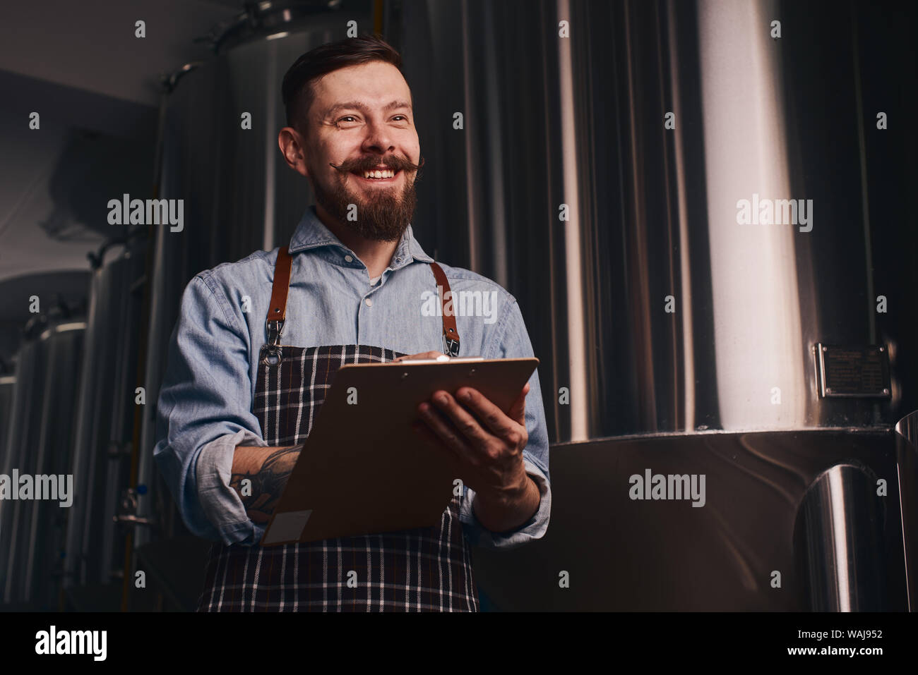 Brewery worker checks how much beer is left in the storage with a