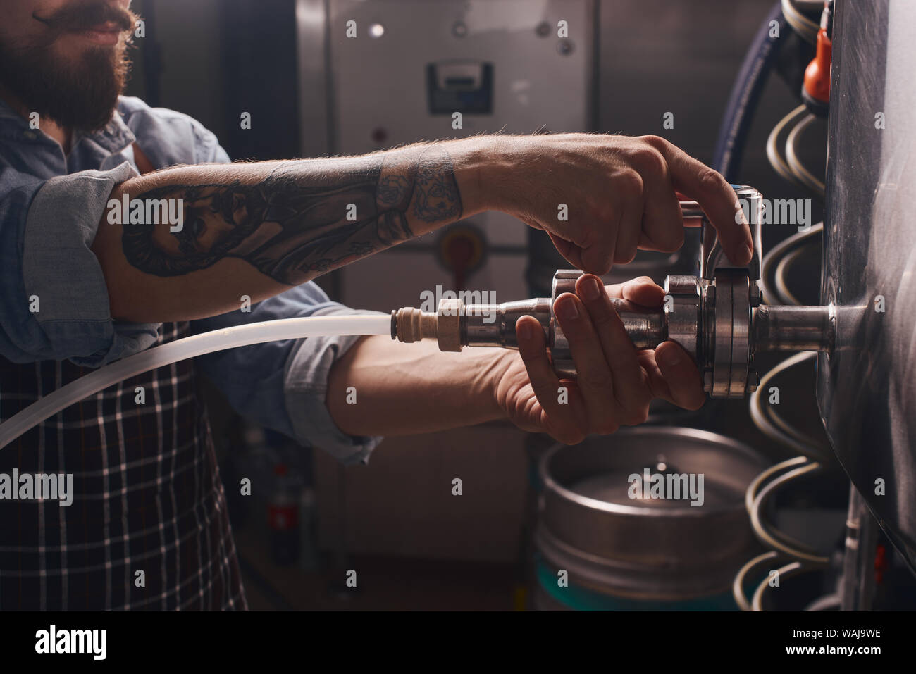 Close up of a man removing taps from the barrels to pour away the rest of the spoiled beer left in it. Stock Photo