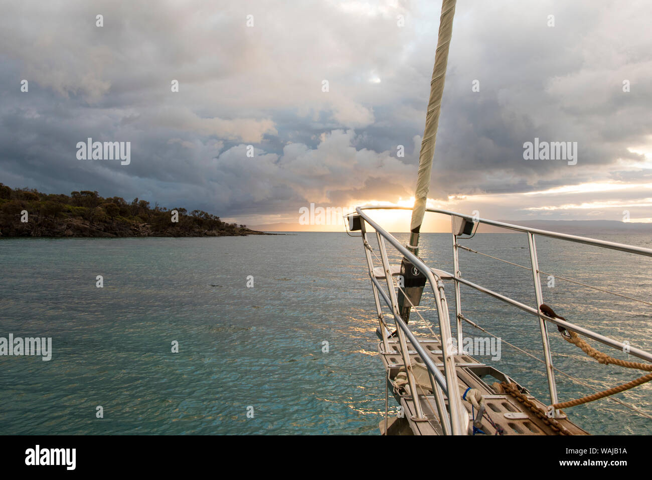 Australia, Tasmania, Freycinet National Park. Morning light breaks through clouds, prow of ship highlighted Stock Photo