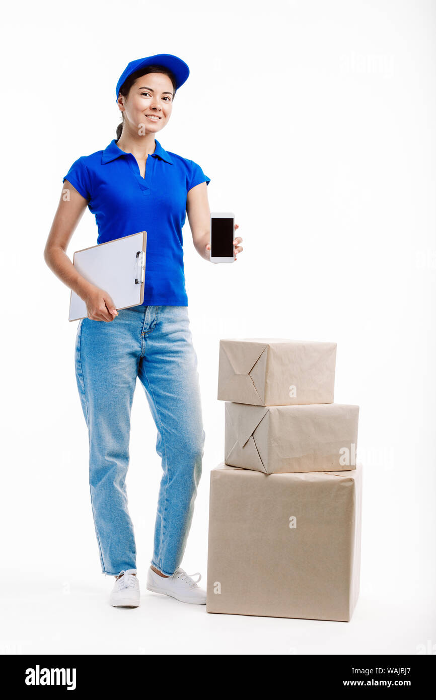 Woman working in delivery has three parcels by her side as she holds a phone in front of her. Stock Photo