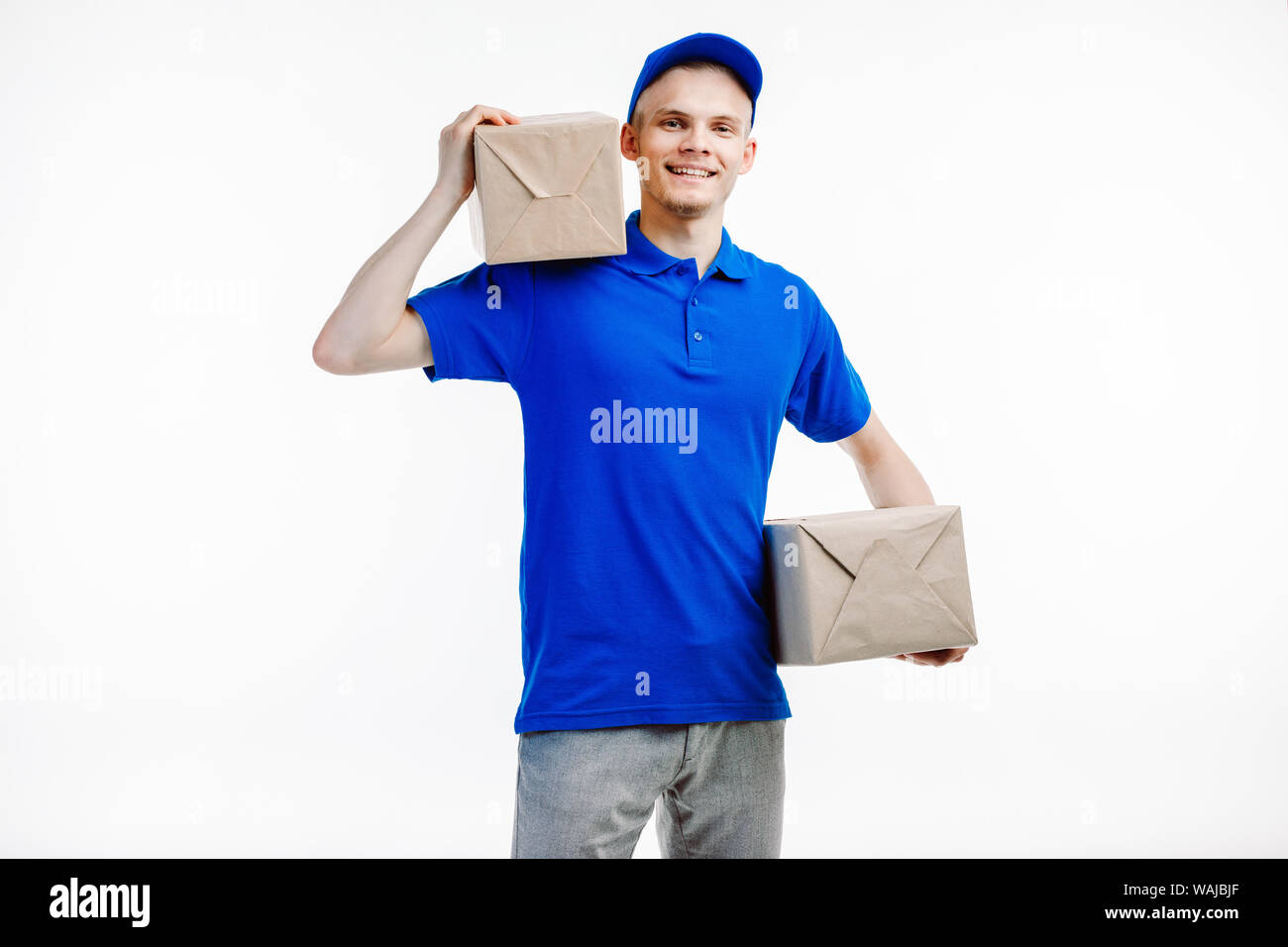 Deliveryman holds two parcles he is about to ship somewhere. Picture taken on the white background. Stock Photo