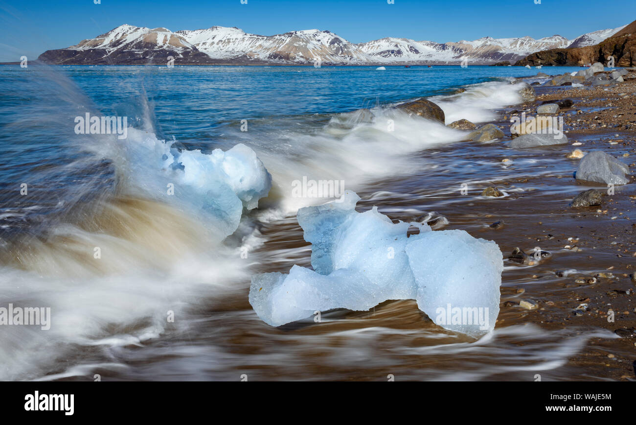 Norway, Svalbard, Spitsbergen. 14th July Glacier, waves crash onto shoreline and glacial ice. Stock Photo