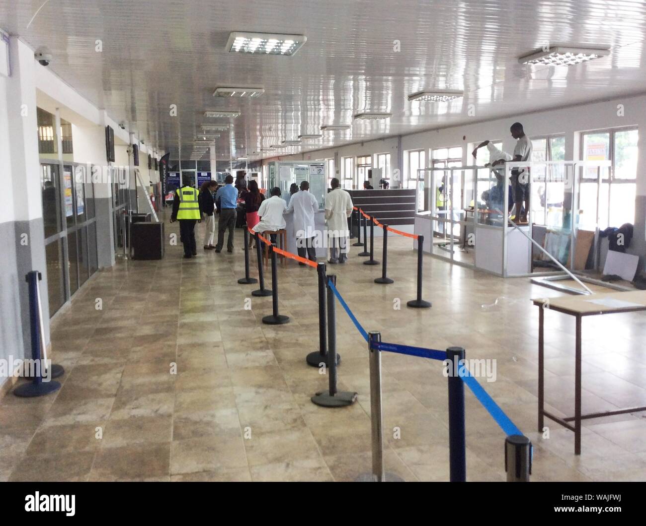This image at the airport in Freetown-Lungi, Sierra Leone depicts Dr. Katrin Kohl of CDC's Border Health Team meeting with the airport authority, and screening staff, in the entranceway to the passenger departure hall. In the center, is the booth where passengers’ temperatures were taken. To the right, an additional booth was being built for better placement of a camera-style infrared thermal detection system, which would screen everyone entering the airport. Stock Photo