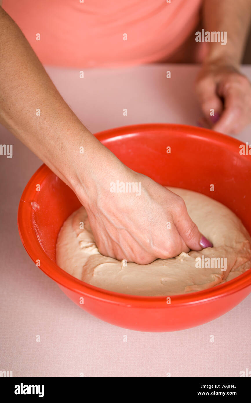 Woman punching down a bowl of naan bread, prior to forming it into the flat bread pieces to be baked. (MR) Stock Photo