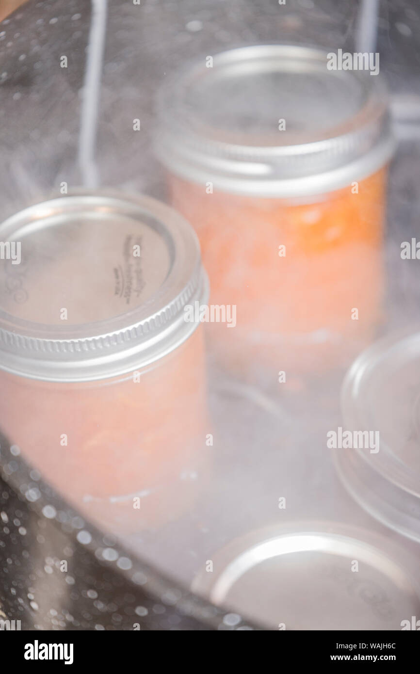Jars of apricot jam resting on a canner rack in a boiling water canner