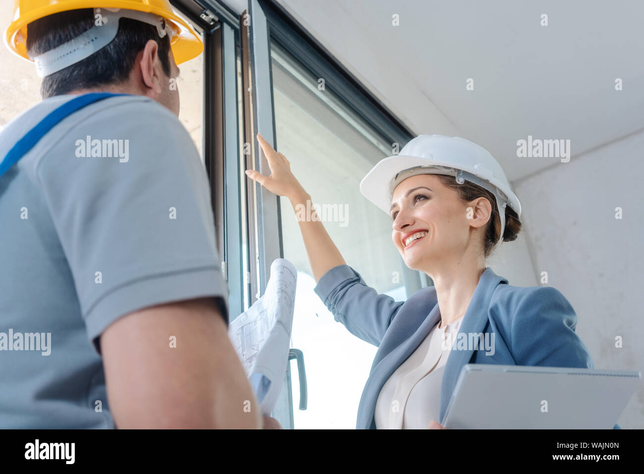 Architect and construction worker checking windows on site Stock Photo