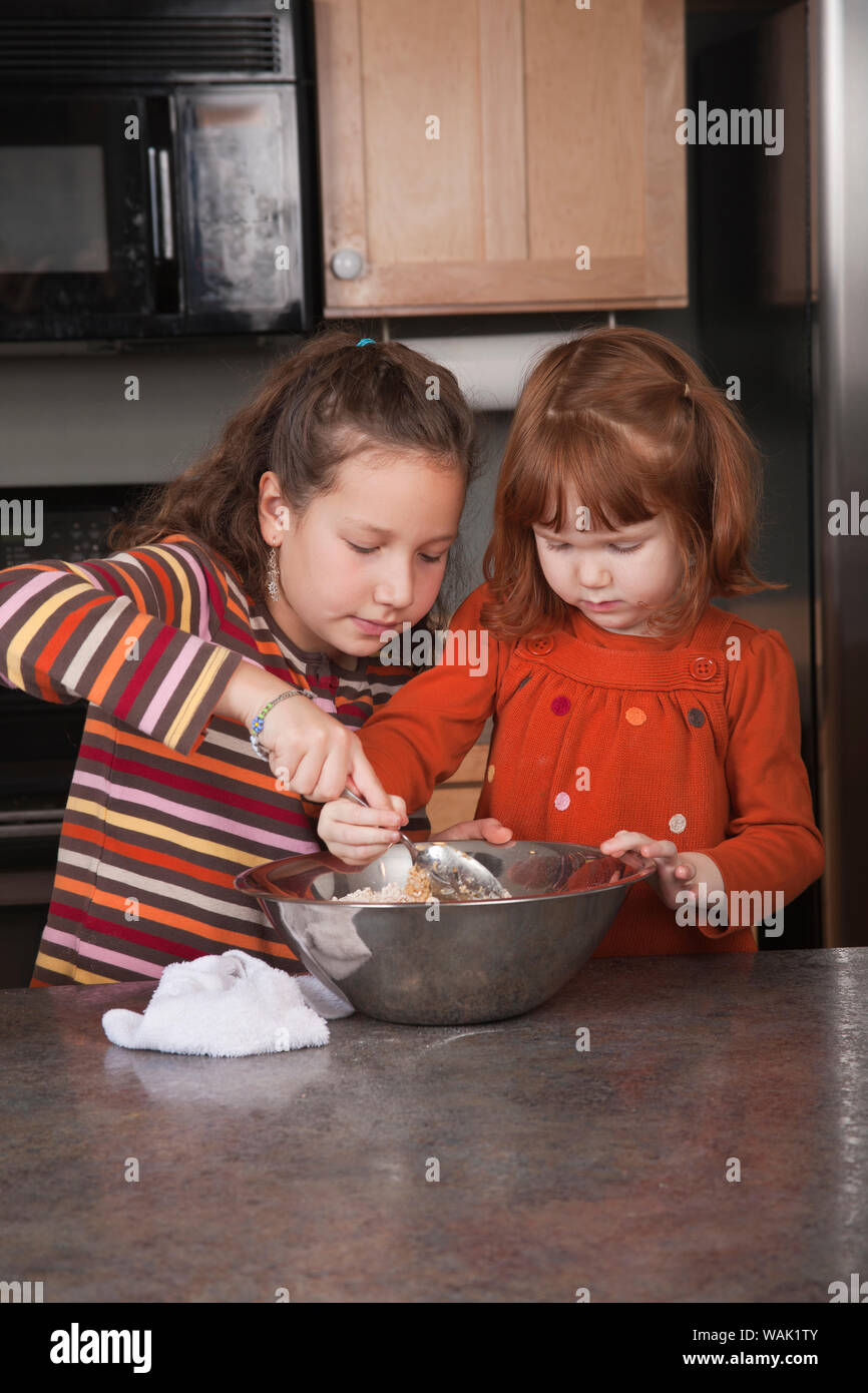 Sisters stirring cookie dough. (MR, PR) Stock Photo