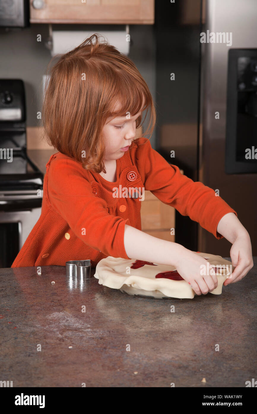 Girl attaching pie dough top to cherry pie. (MR, PR) Stock Photo
