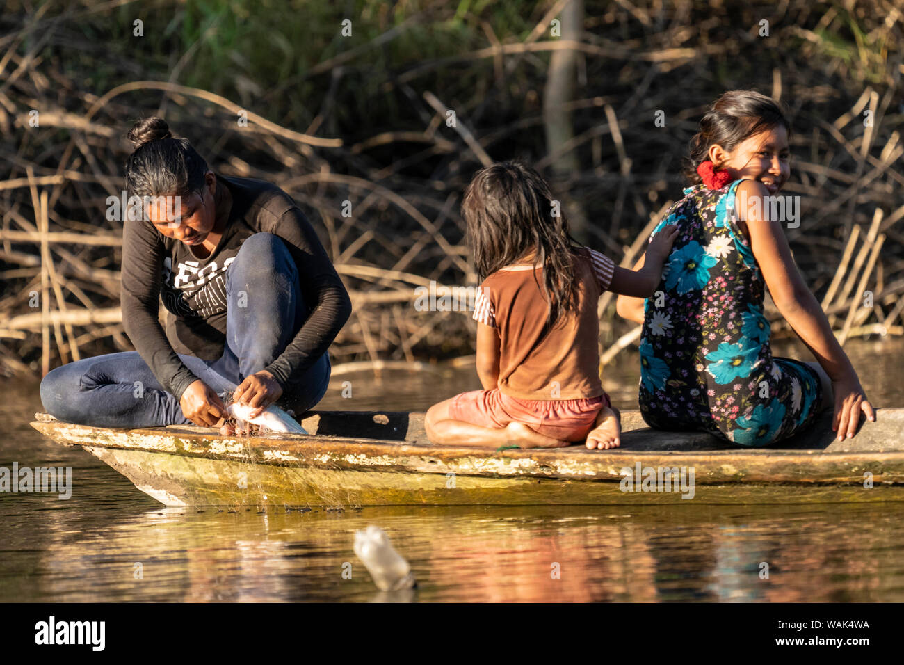 Pacaya Samiria Reserve, Peru. Woman with her two daughters in a dugout canoe, removing a fish from a net. (Editorial Use Only) Stock Photo