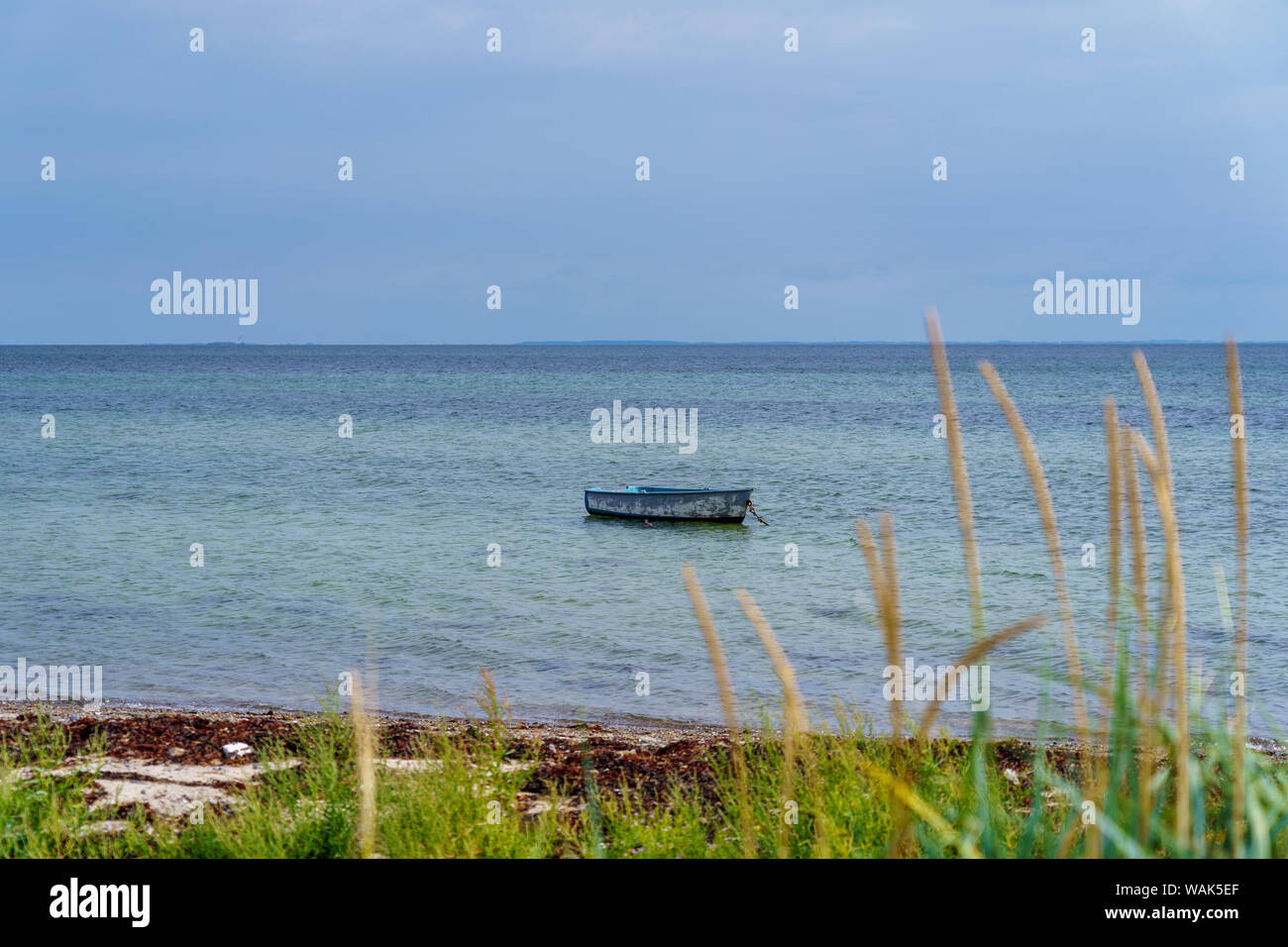 Small boat drifts in the water on the coast with a wide view over the Baltic Sea Stock Photo
