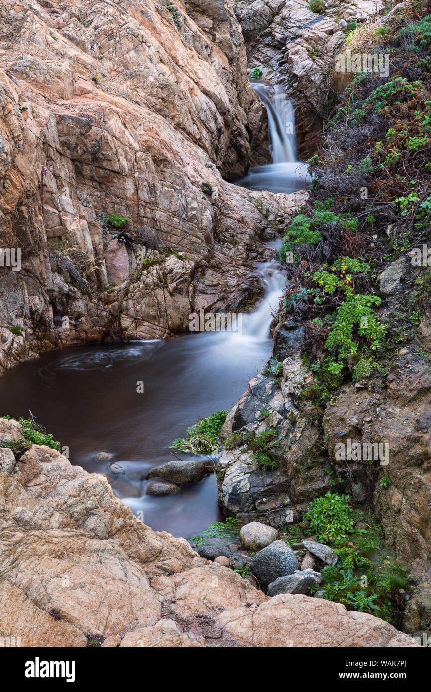 Long exposure of a stream and water falling through craggy rocks Stock Photo
