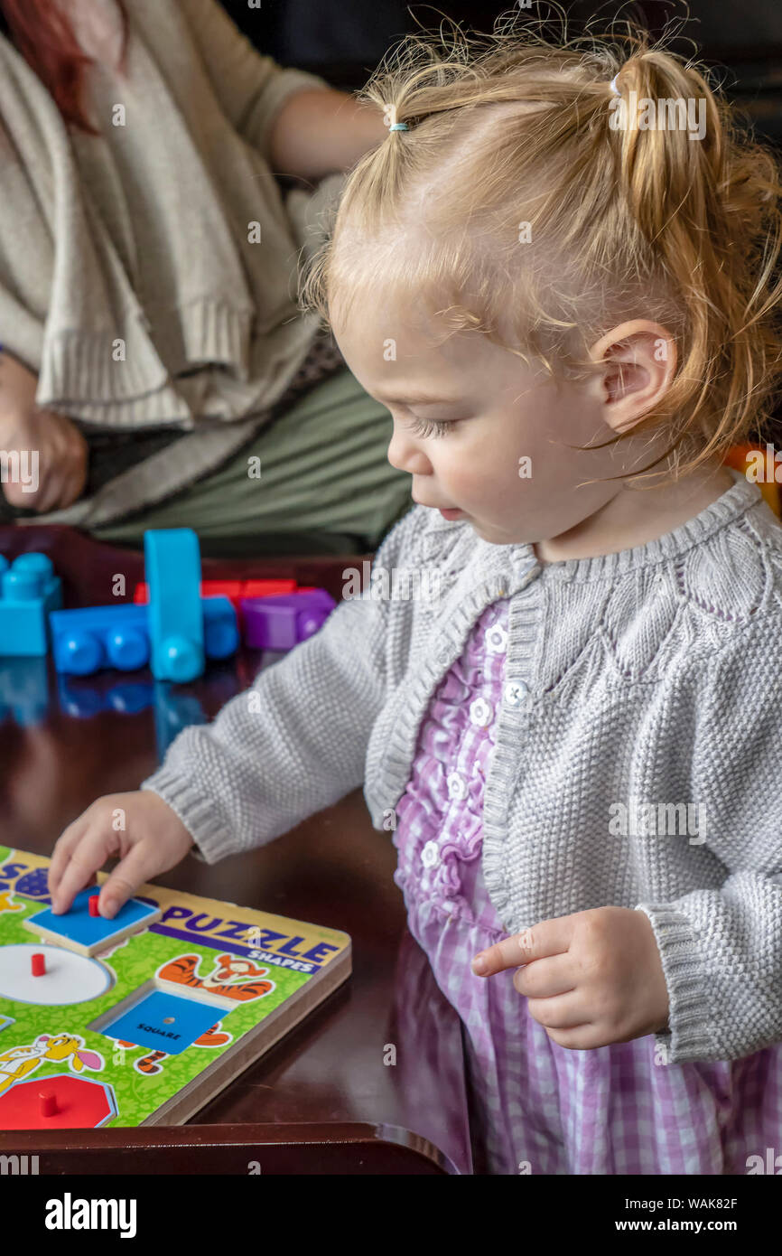 19 month old girl putting a wooden puzzle together. (MR) Stock Photo