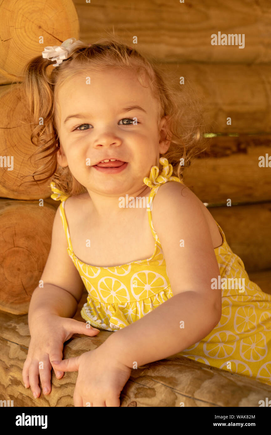 Eatonville, Washington State, USA. 18 month old girl playing in a children's sized log cabin. (MR) Stock Photo