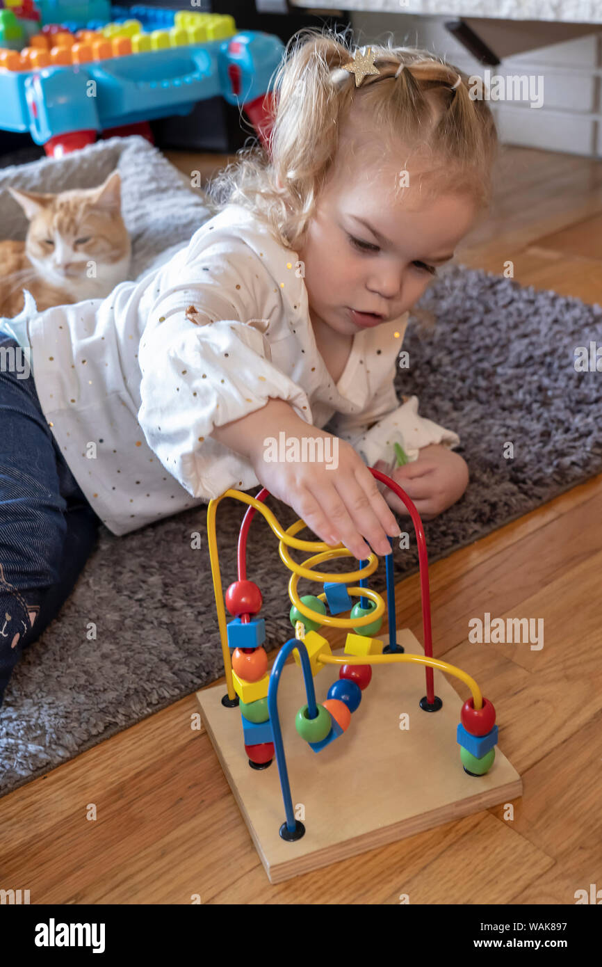 2 year old playing with a bead toy, thinking about how to make the beads move. (MR,PR) Stock Photo