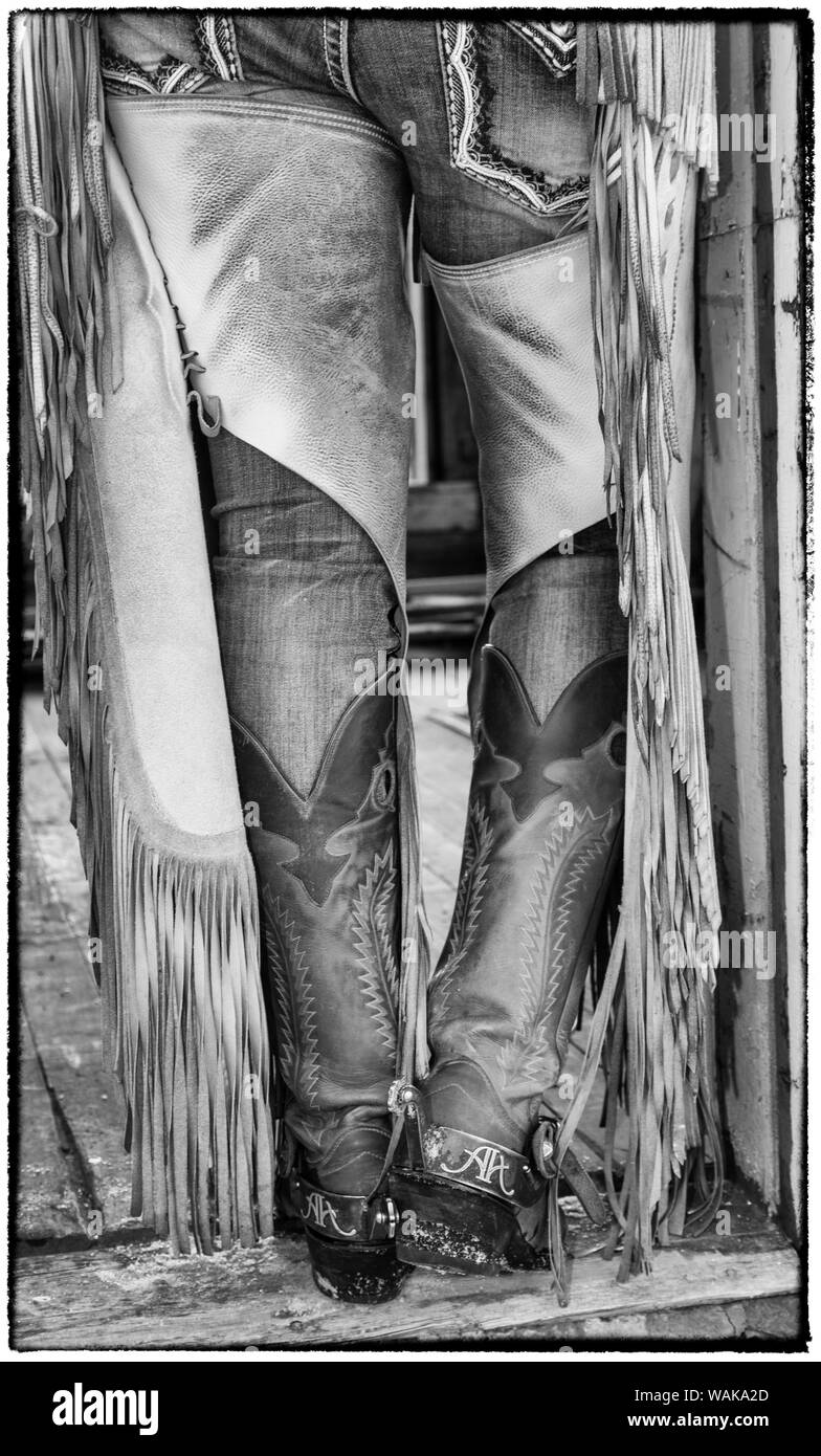 Horse drive in winter on Hideout Ranch, Shell, Wyoming. Cowgirl detail of boots and chaps in doorway of log cabin. Stock Photo
