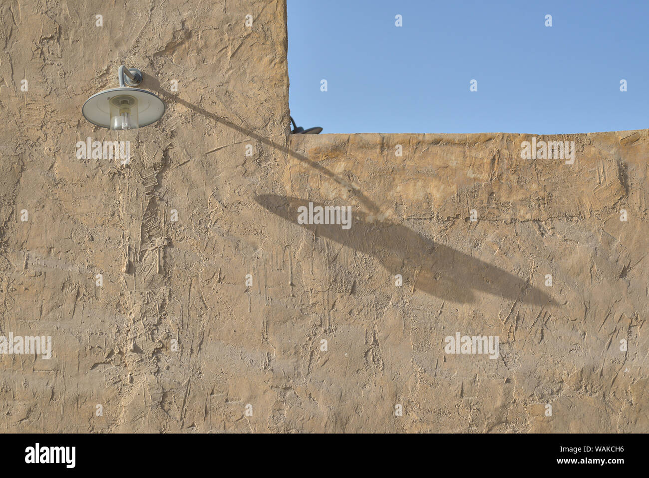 Vintage lighting fixture casting a shadow, taken in the afternoon with traditional house wall in the foreground, Souq Wakrah, Qatar Stock Photo