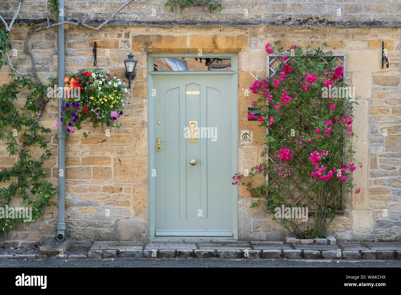 Cotswold stone town house with pink climbing roses and a hanging basket in the market place of Stow on the Wold, Cotswolds, Gloucestershire, England Stock Photo
