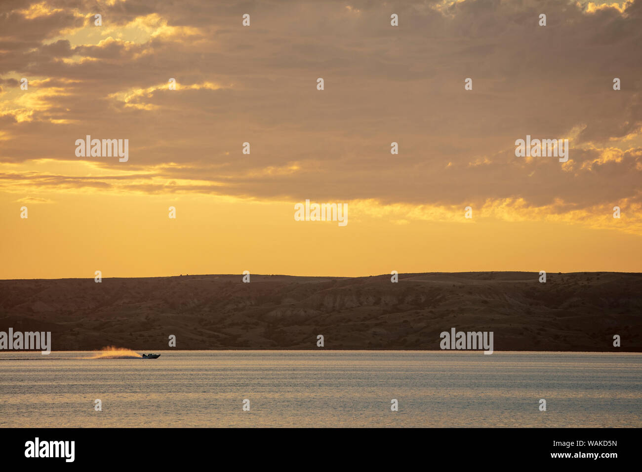 Fishing boat races along at sunrise on Fort Peck Reservoir near Fort