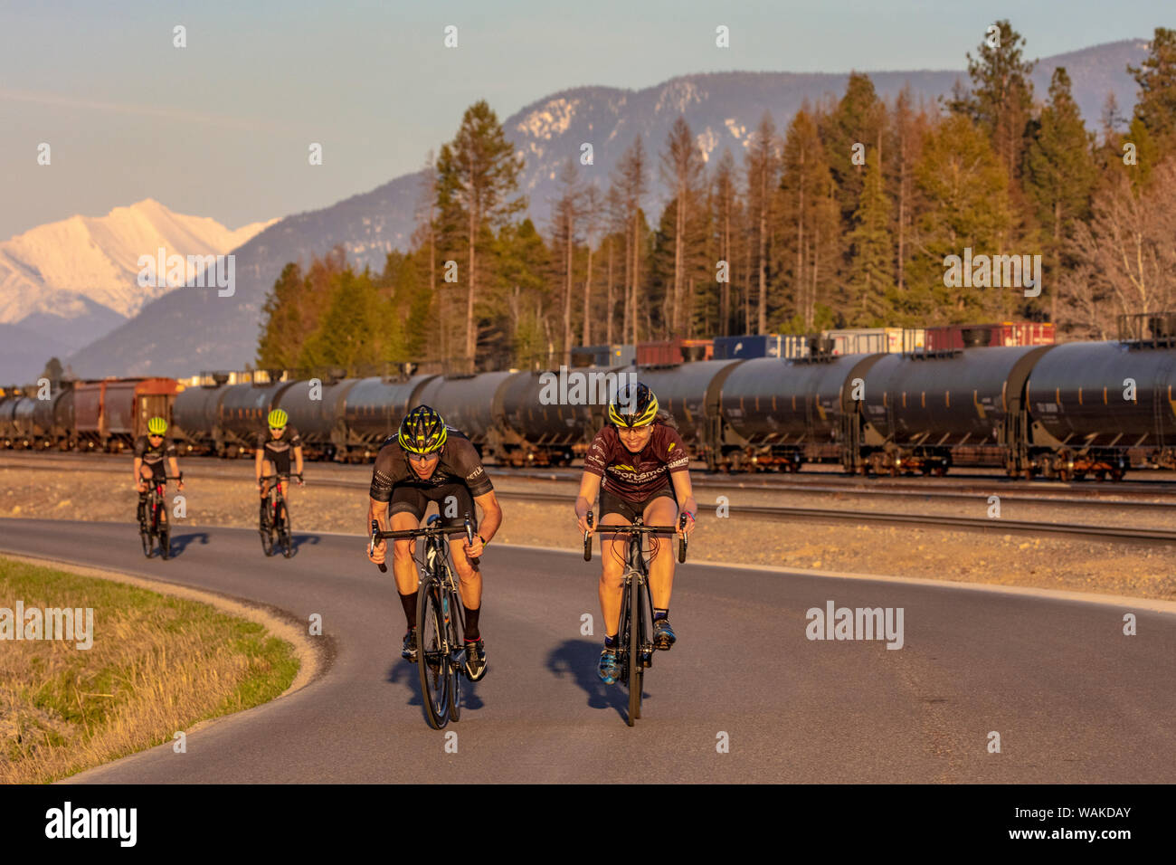Family road bicycling on Edgewood Road with Great Northern Mountain and railyard in the background in Whitefish, Montana, USA (MR) Stock Photo
