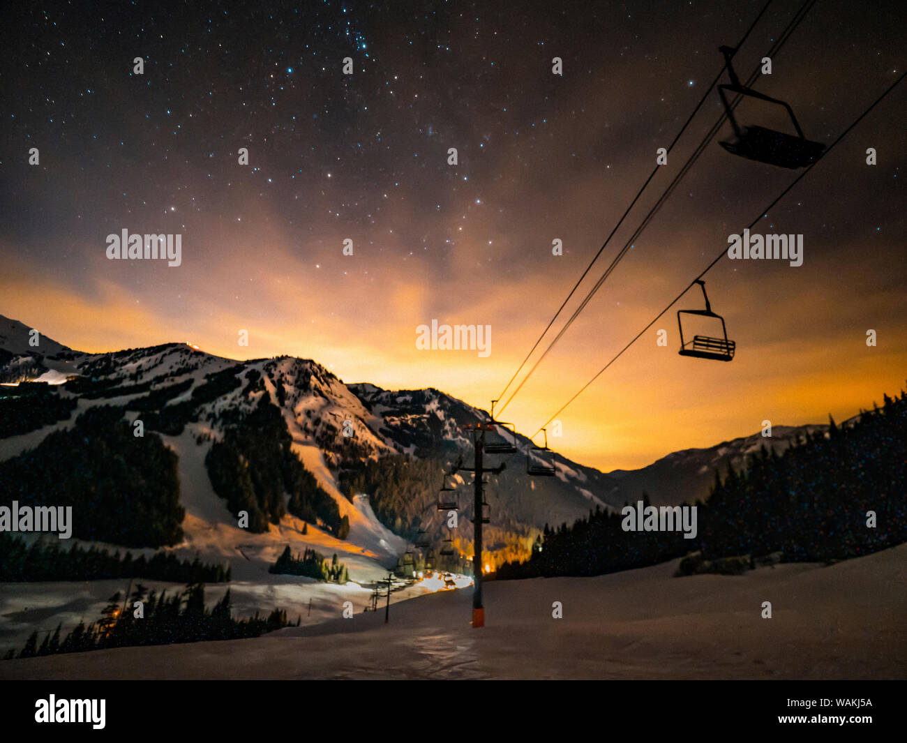 USA, Washington State, Pierce County, Crystal Mountain Resort. Chairlift in front of starry dusk sky as sun sets behind mountains. Stock Photo