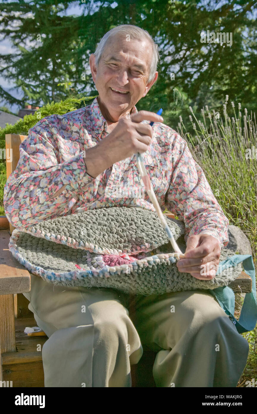 Seattle, Washington State, USA. Man toothbrush weaving of a rag rug at his home. (MR, PR) Stock Photo