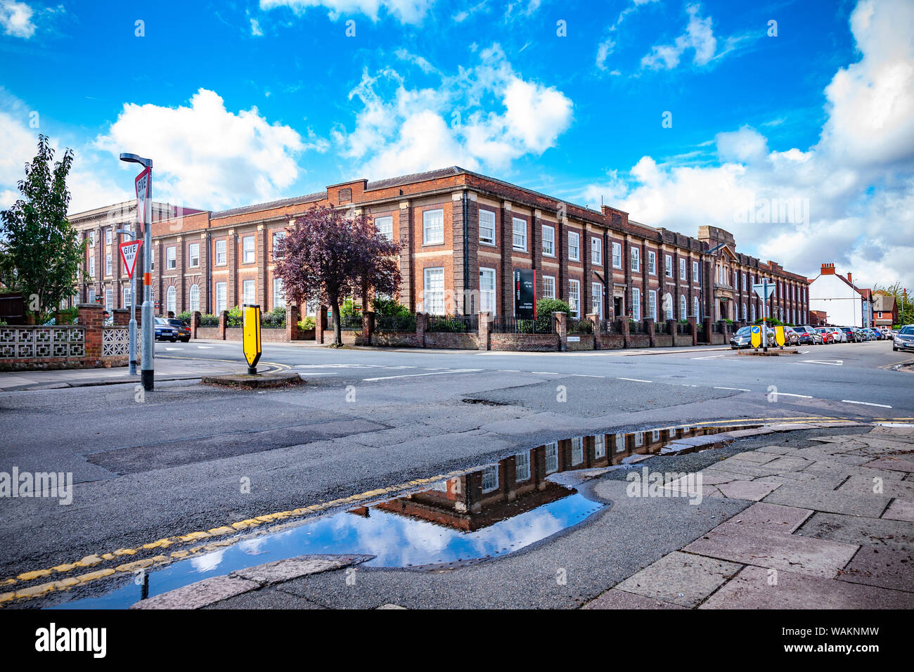 After heavy overnight rain sunshine and blue clouds  appear early morning, reflecting in the rain puddles on Christchurch road opposite Mobbs Miller h Stock Photo