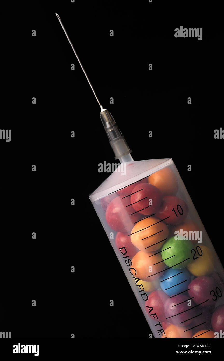 Close up of a syringe filled with candy on a black background Stock