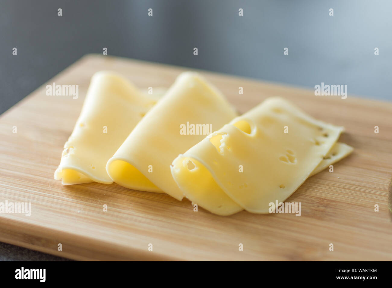 Slices of cheese on wooden background. Holland cheese with holes. Stock Photo