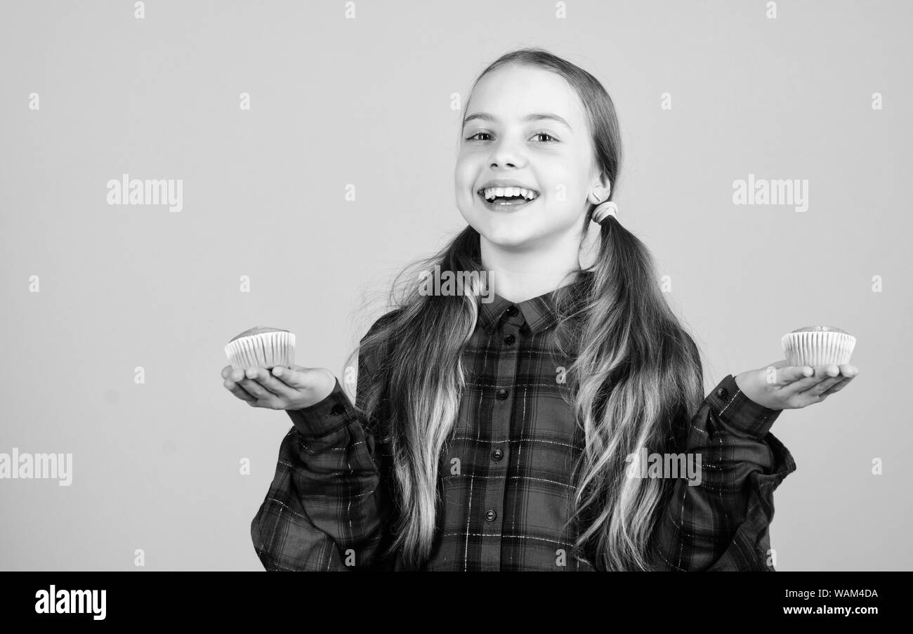 The perfect dessert from our bakery. Happy cute little girl holding cupcakes in bakery shop