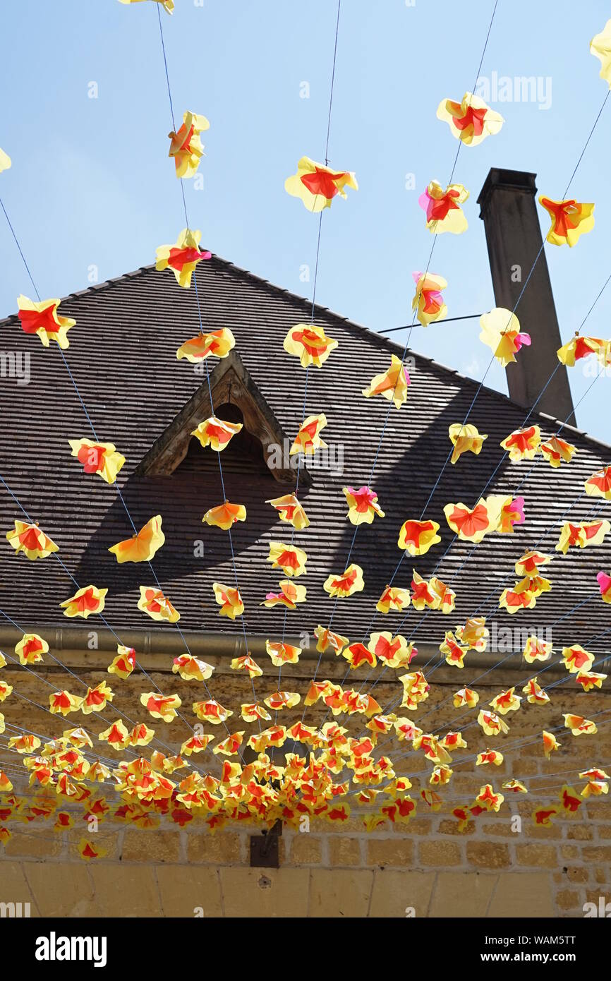Flower decorations hanging in the air with a roof top behind Stock Photo