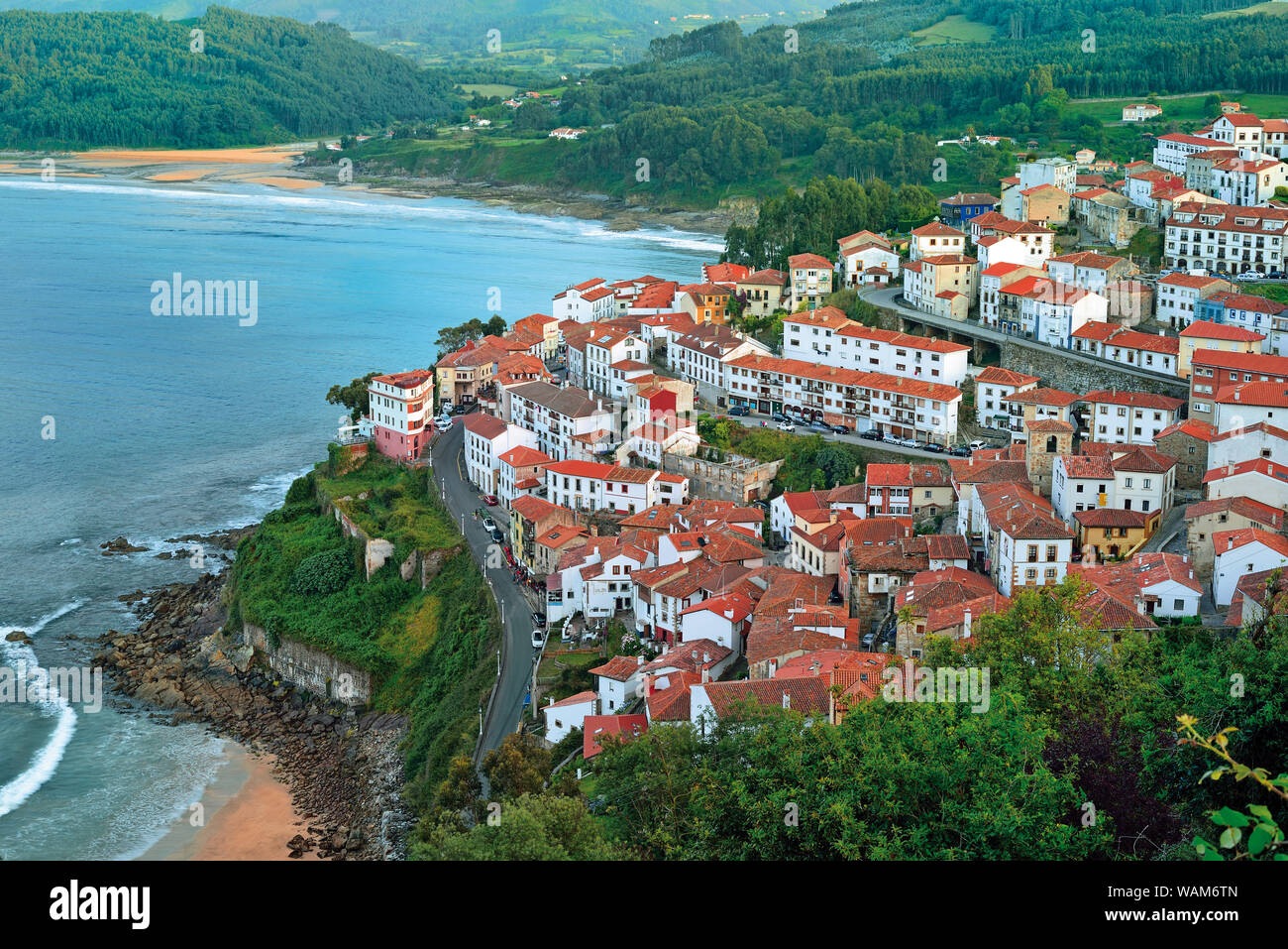 View to small coastal village with green mountains and sand beaches Stock Photo