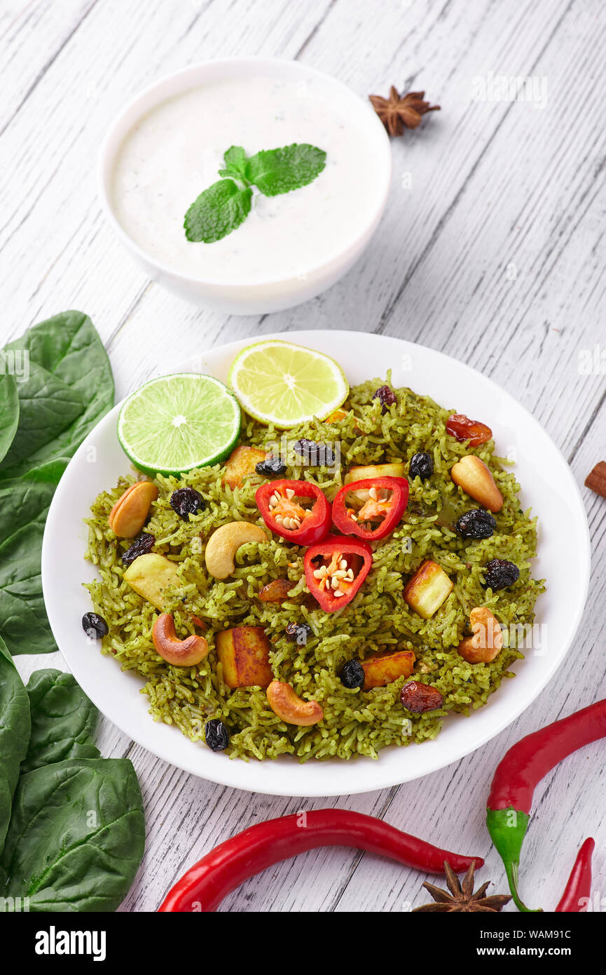 Palak Paneer Biryani and Raita at white wooden background with decor