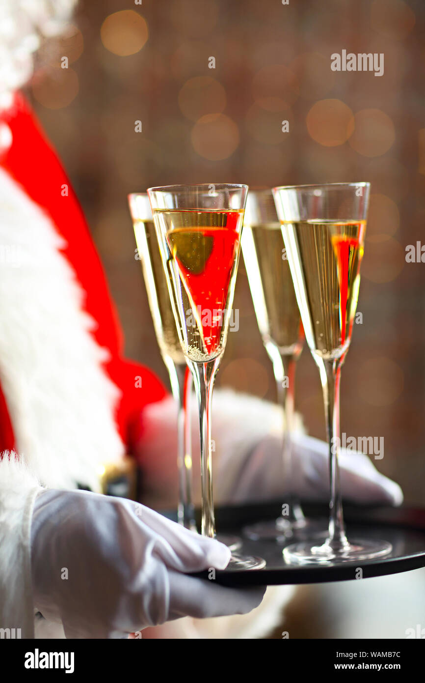 Santa Claus holding champagne glasses on the tray. Closeup Stock Photo