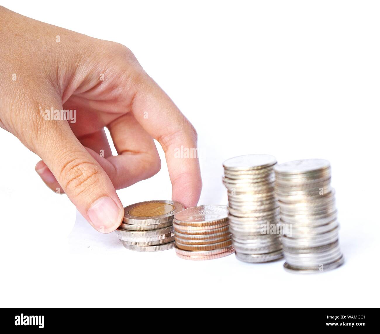 Hand picking money from four stacks coins row on white background, Financial and commit business concept Stock Photo