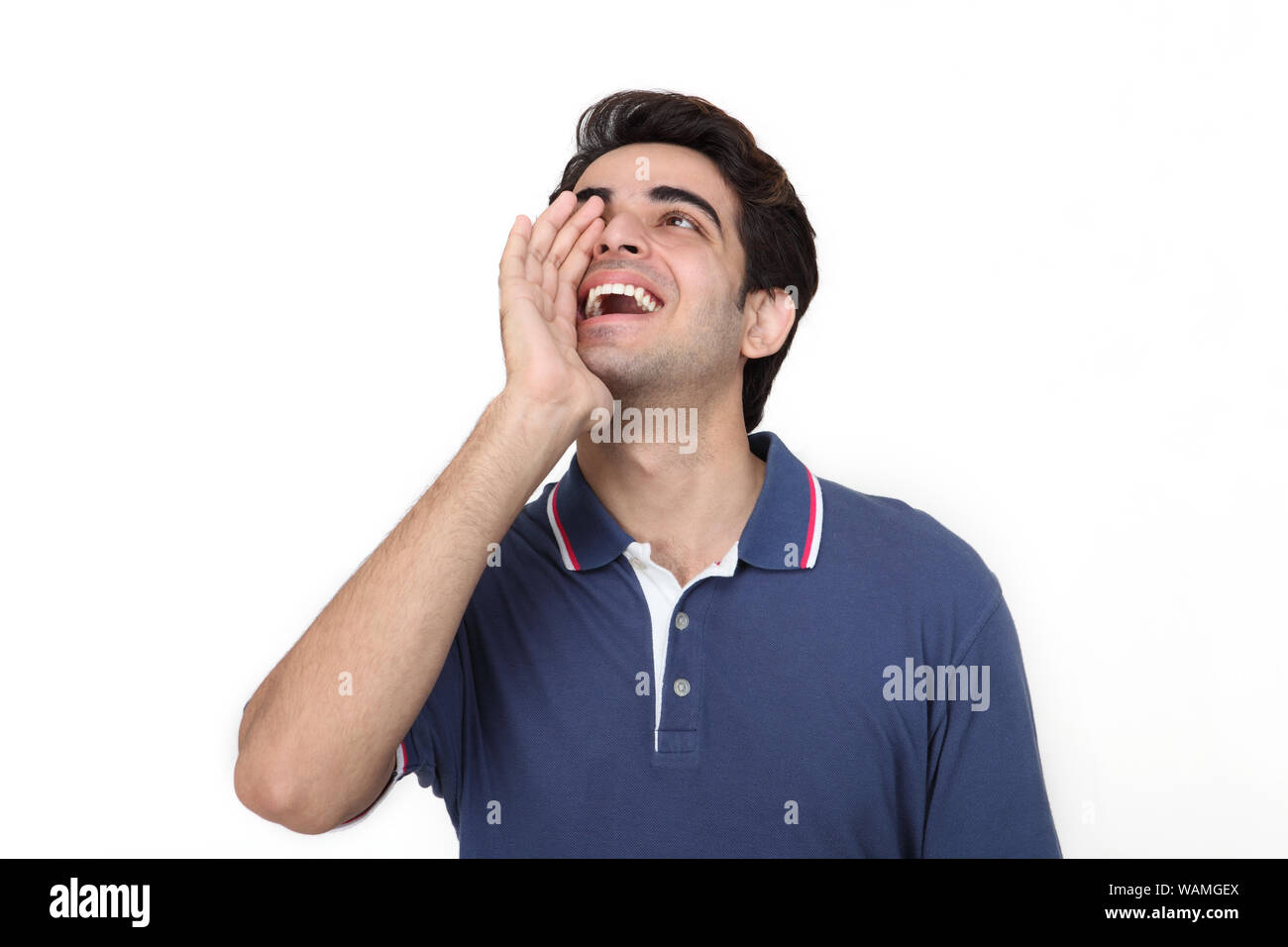 Indian young man shouting with hands cupping mouth Stock Photo