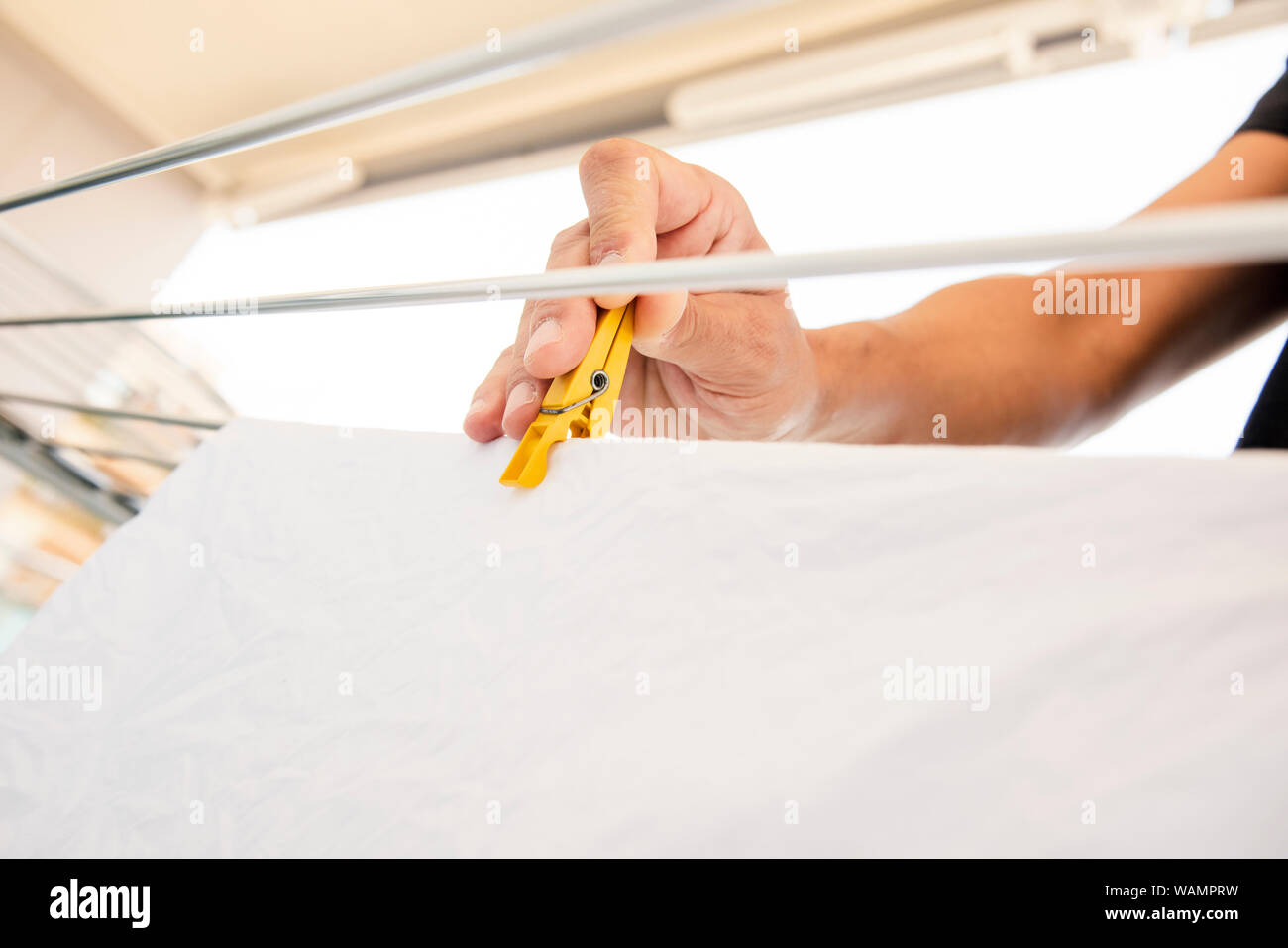 closeup of a young caucasian man hanging wet clothes on a drying rack
