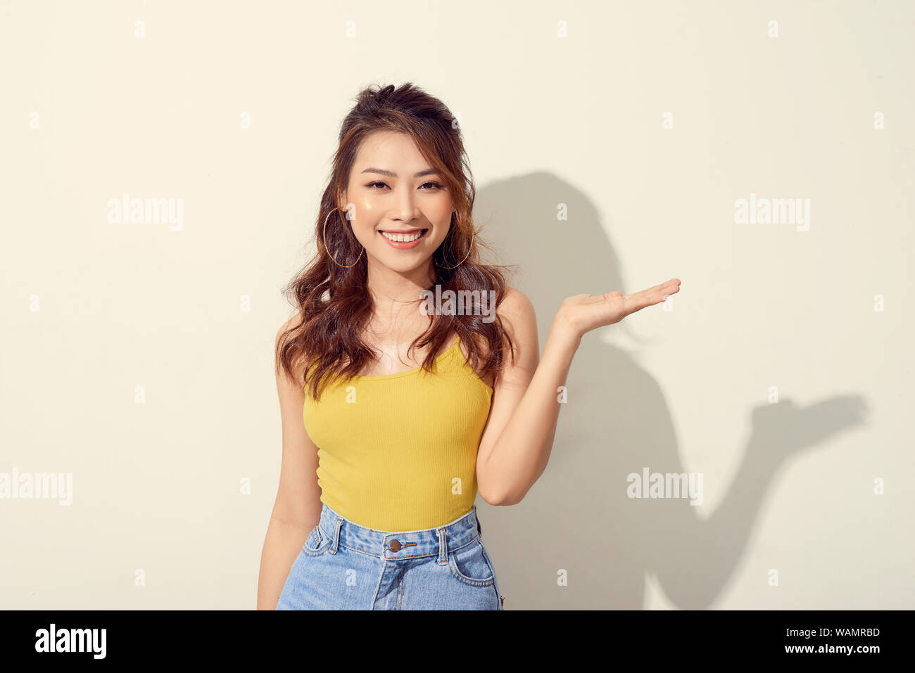 Smiling asian woman showing open hand palm to to the copy space for ...