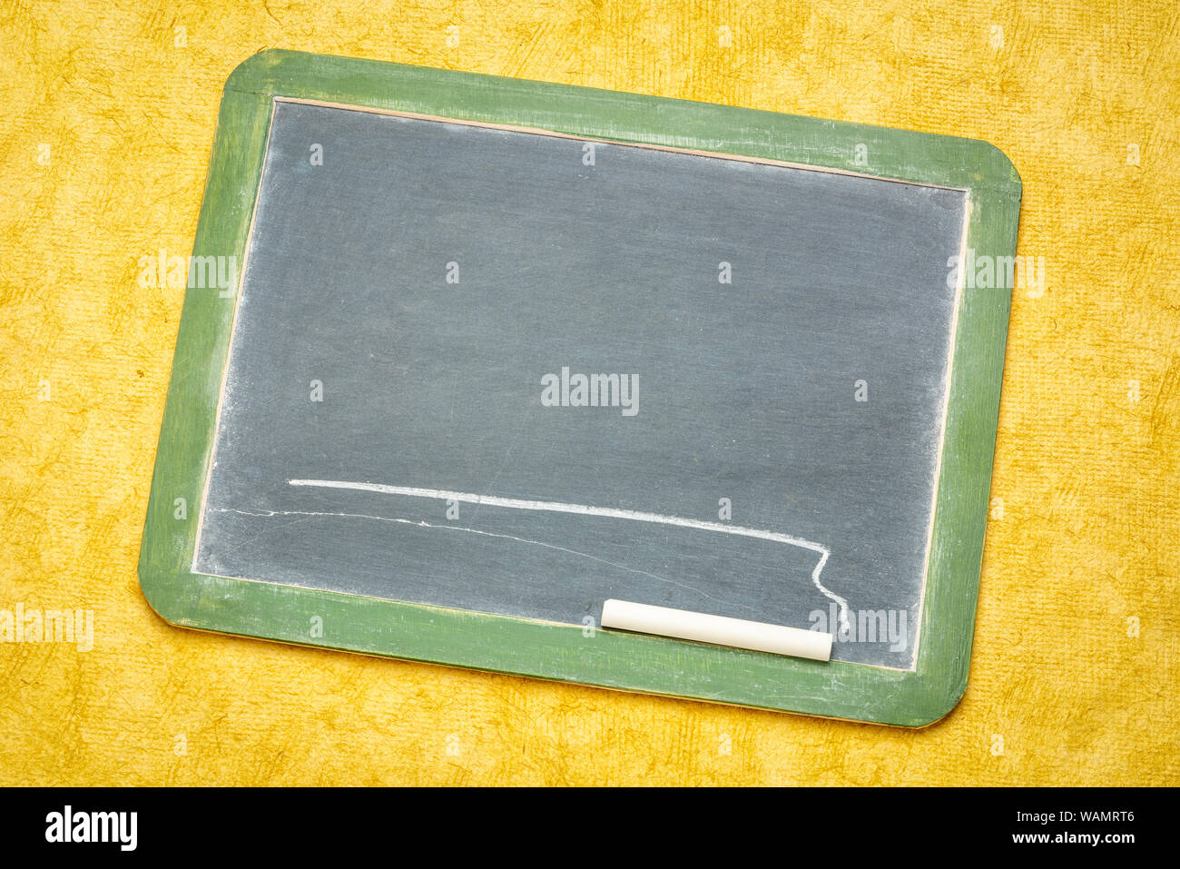 blank slate blackboard with a white chalk against yellow textured bark