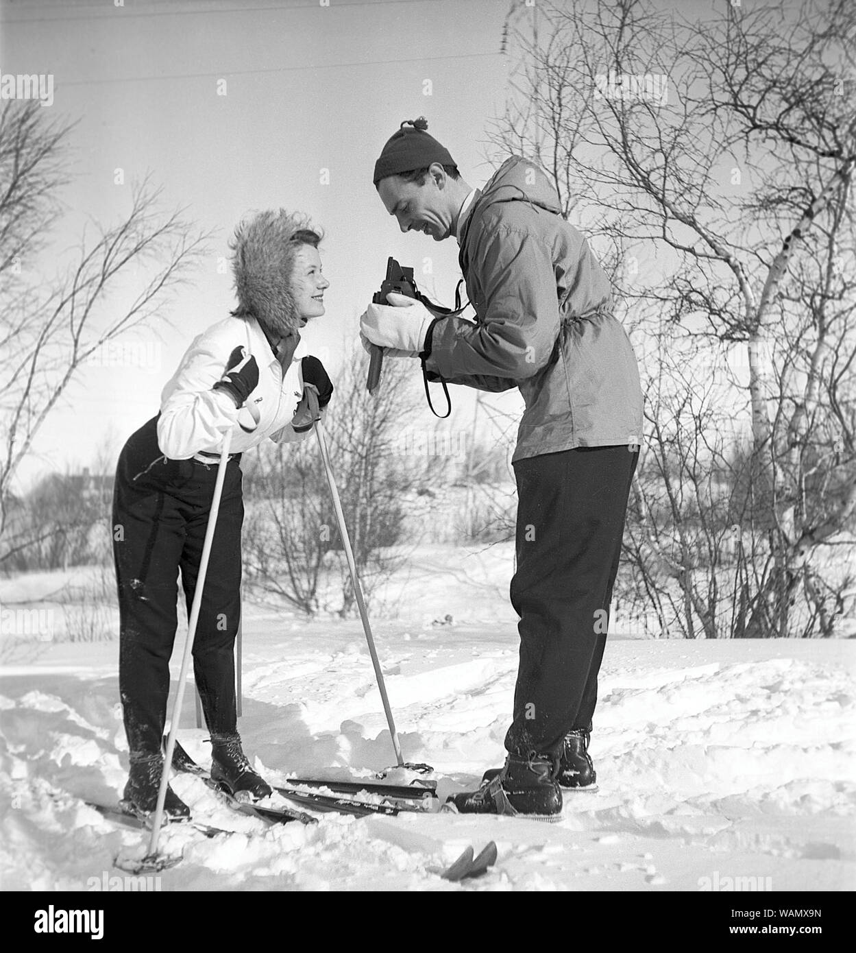 Winter in the 1940s. Actor Nils Kihlberg, 1915-1965 is pictured here with his wife Ann-Britt. He is taking pictures of her on their winter vacation. They are both wearing winter clothes and skis.  The camera is a Rolleiflex by german company Rollei.  Sweden 1943. Kristoffersson Ref D70-2 Stock Photo