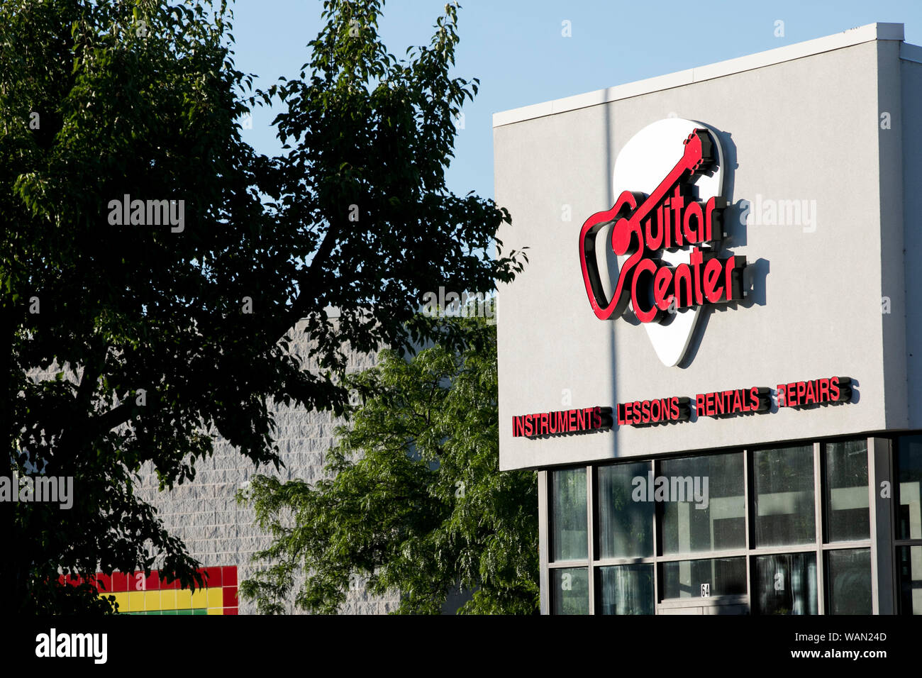 A logo sign outside of a Guitar Center retail store location in Orem